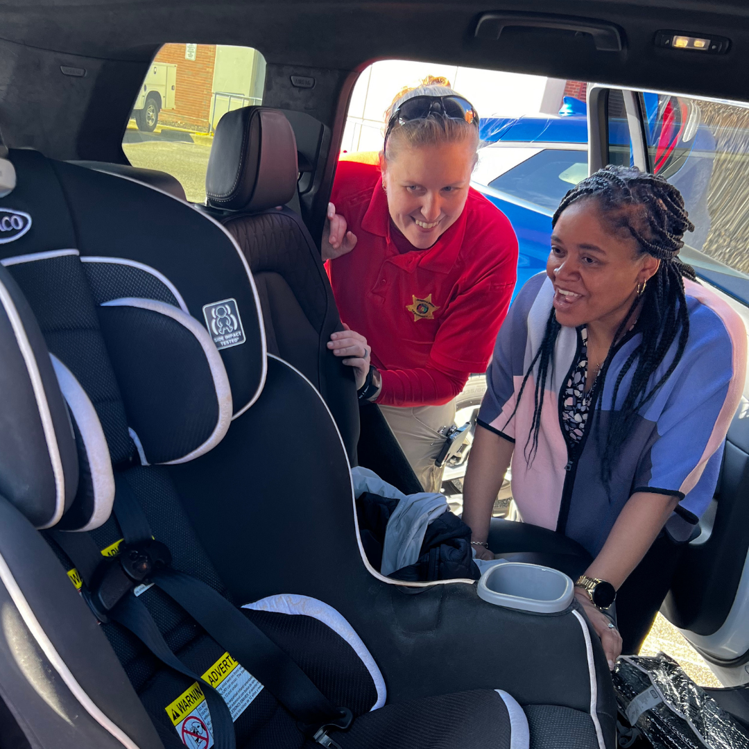 Deputy helping a parent install a child car seat