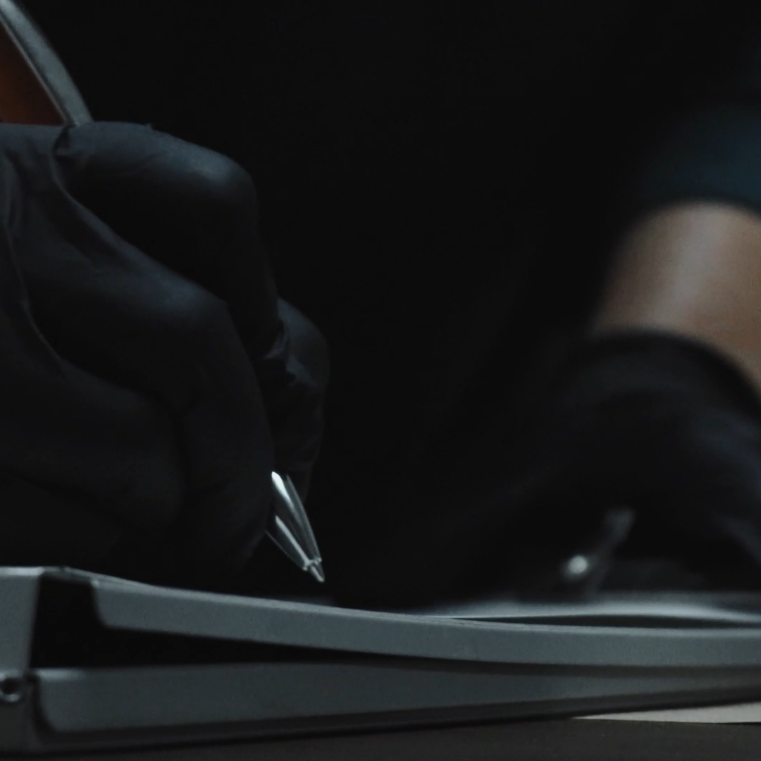 Gloved investigator writing notes in low light